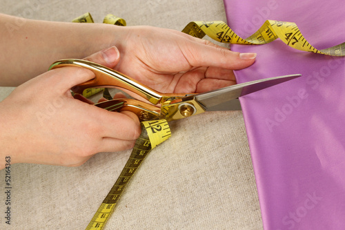 Photo: Seamstress cut green fabric close-up Seamstress cut green fabric close-up
