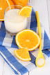 Delicious yogurt in glass with orange on wooden table close-up