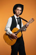 Retro country male guitar player wearing black suit and hat. Stu