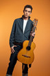 Retro fifties musician holding his guitar wearing grey jacket. S