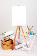 Wooden easel with clean paper and art supplies in room