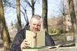 Foto: Man reading a book outdoors on a bench Man reading a book outdoors on a bench