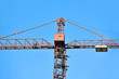Foto: Red construction tower crane against blue sky Red construction tower crane against blue sky