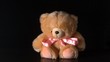 Teddy bear with pink ribbon falling on black background