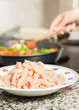 Closeup of raw chiken dish and female cooking in a pan in the ba