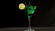 Ice cube falling into green cocktail