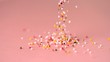 Loads of sprinkles falling on pink surface