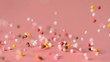 Loads of sprinkles falling on pink surface and rolling across