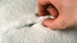 Hand lifting syringe out of pile of sugar