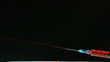 Syringe of blood squirting on black background