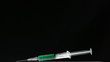 Syringe of green liquid falling and bouncing on black surface