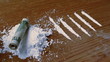 Rolled up note falling on white substance with lines 