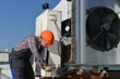Air Conditioning Repair, young repairman on the roof fixing AC