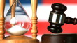 Gavel dropping on sounding block beside hourglass