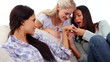 Close up of woman showing engagement ring to friends sitting