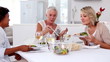 Mature woman serving meal to her friends in the dinning room