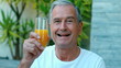 Retired man toasting with orange juice outside in slow motion