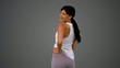 Fit brunette turning and smiling on grey background