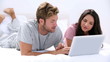 Couple using the laptop lying bed