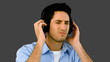 Man listening to music with headphones on grey background