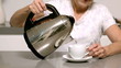 Woman pouring boiling water from kettle into cup