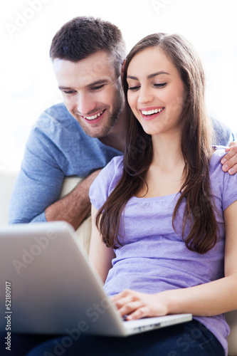 Photo: Young couple using laptop Young couple using laptop