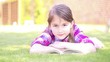 Little girl reading a book in summer on grass.Girl  Reading