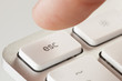 Finger Pressing Escape on a Grey Computer Keyboard