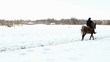 female cowboy rides a horse at a gallop in winter