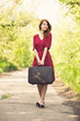Redhead girl with suitcase at tree's alley.