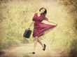 Redhead girl with suitcase at tree's alley.