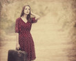 Redhead girl with suitcase at tree's alley.