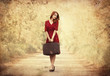 Redhead girl with suitcase at tree's alley.