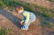 little child in the jeans coverall pick up stones