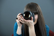 Young woman with DSLR over dark background