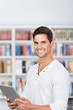 Photo: lächelnder mann mit tablet in der bibliothek lächelnder mann mit tablet in der bibliothek