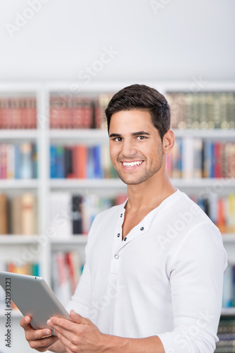 Photo: lächelnder mann mit tablet in der bibliothek lächelnder mann mit tablet in der bibliothek