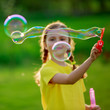Summer joy - lovely girl blowing soap bubbles