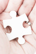 Palm of human hand hold white piece of a puzzle