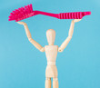 Female wooden doll holding red dish brush