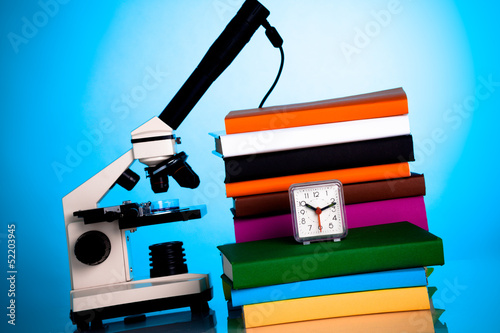 Photo: Mikroskop, Bücher und ein Wecker auf dem Studenten Tisch Mikroskop, Bücher und ein Wecker auf dem Studenten Tisch