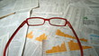 Glasses falling over sheets of paper showing yellow charts