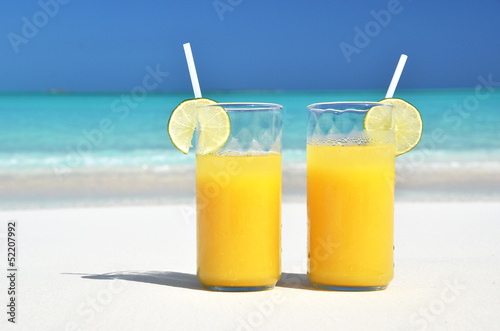 Photo: Two glasses of orange juice on the sandy beach Two glasses of orange juice on the sandy beach