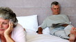 Husband reading newspapers while his wife is thinking