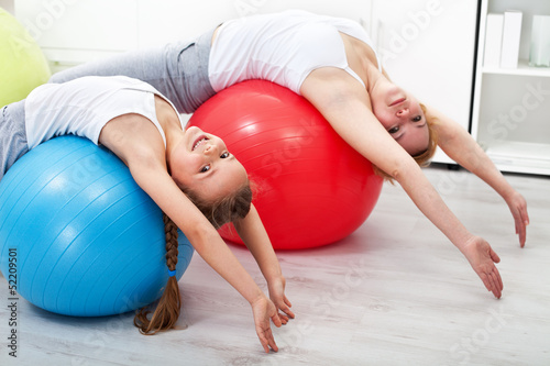 Photo: Woman and little girl doing stretching exercises Woman and little girl doing stretching exercises