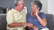 Mature couple having a phone conversation while reading a book
