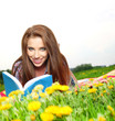 Beautiful girl lies on meadow and reads the boo