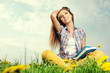 Beautiful girl lies on meadow and reads the boo