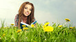 Beautiful girl lies on meadow and reads the boo