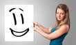 Young woman holding smiley face drawing